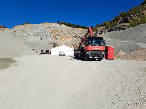 Carrière à ciel ouvert avec fronts de taille, zones de stockage et équipements de manutention des granulats.
