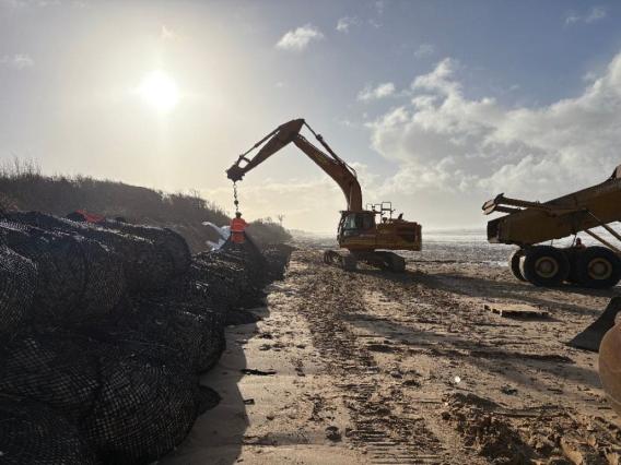 Installation de gabions en bord de mer pour stabilisation du trait de côte, chantier d’aménagement côtier avec engins.