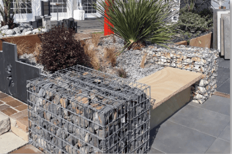 Aménagement de jardin avec structures en gabions et granulats, mobilier extérieur et soutènement paysager.