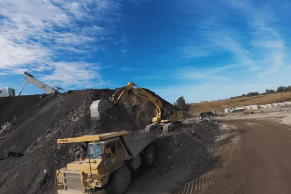 Pelle mécanique chargeant des matériaux recyclés dans un tombereau sur une plateforme de recyclage de granulats en carrière Nexstone