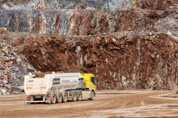 Camion électrique en carrière Nexstone transportant des granulats au pied d’un front de taille rocheux