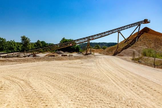 Vue d'une carrière Nexstone avec une installation de convoyage et des stocks de granulats, illustrant la production de matériaux minéraux pour les travaux de construction.