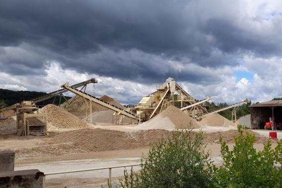 Installation de traitement des granulats sur une carrière Nexstone, avec convoyeurs et stocks de matériaux minéraux destinés aux travaux de construction et d'aménagement.