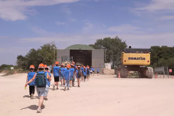 Groupe d'élèves en visite de la carrière de Bainville, accompagnés sur le site d'exploitation à proximité des installations et des engins de chantier.