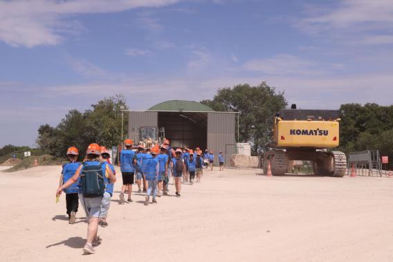 Groupe d'élèves en visite de la carrière de Bainville, accompagnés sur le site d'exploitation à proximité des installations et des engins de chantier.