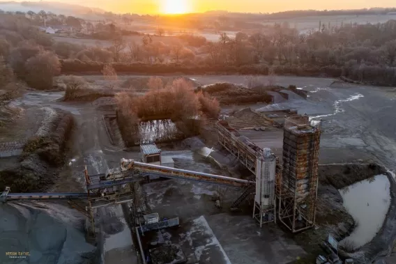 Vue aérienne des installations de traitement de la carrière de Plumelin avec convoyeurs et silos de production.