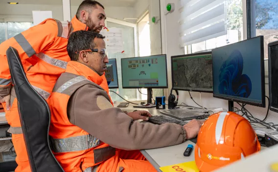 Collaborateurs Nexstone en tenue de sécurité analysant des données sur écrans de contrôle, dans un environnement de supervision industrielle.