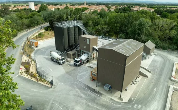 Centrale à béton de Cuxac-d’Aude vue aérienne, avec silos de stockage, zone de chargement des camions toupies et bâtiments techniques au cœur d’un site industriel entouré de végétation.