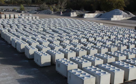 Blocs béton préfabriqués, appelé Nexbrick, alignés sur plateforme de matériaux, utilisés pour l’aménagement, le stockage et la construction d’infrastructures et d’ouvrages techniques