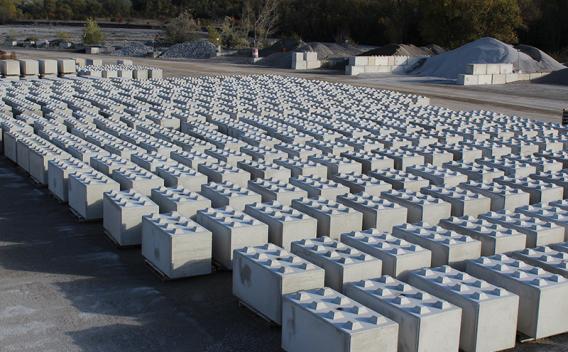 Blocs béton préfabriqués, appelé Nexbrick, alignés sur plateforme de matériaux, utilisés pour l’aménagement, le stockage et la construction d’infrastructures et d’ouvrages techniques