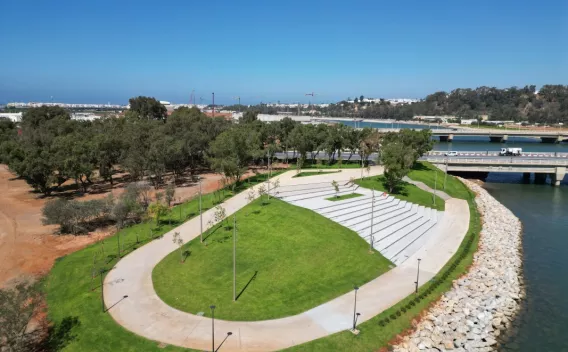 Aménagement urbain paysager en bord de rivière avec cheminements piétons, espaces verts et ouvrages en matériaux minéraux.
