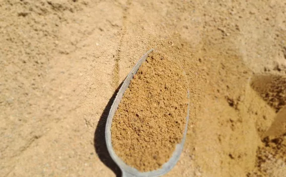 Sable granulaire utilisé en construction et aménagement, présenté à la pelle sur un stock de matériau minéral