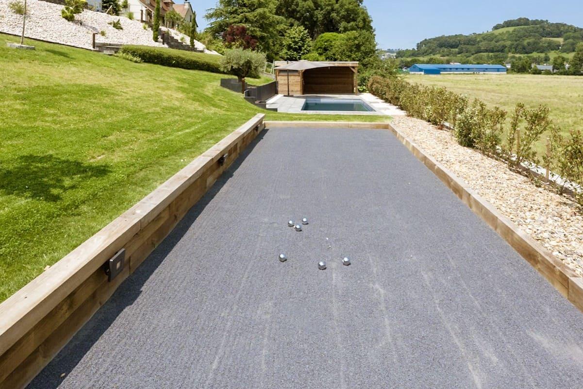Terrain de pétanque en basalte avec revêtement minéral pour aménagement extérieur résidentiel.