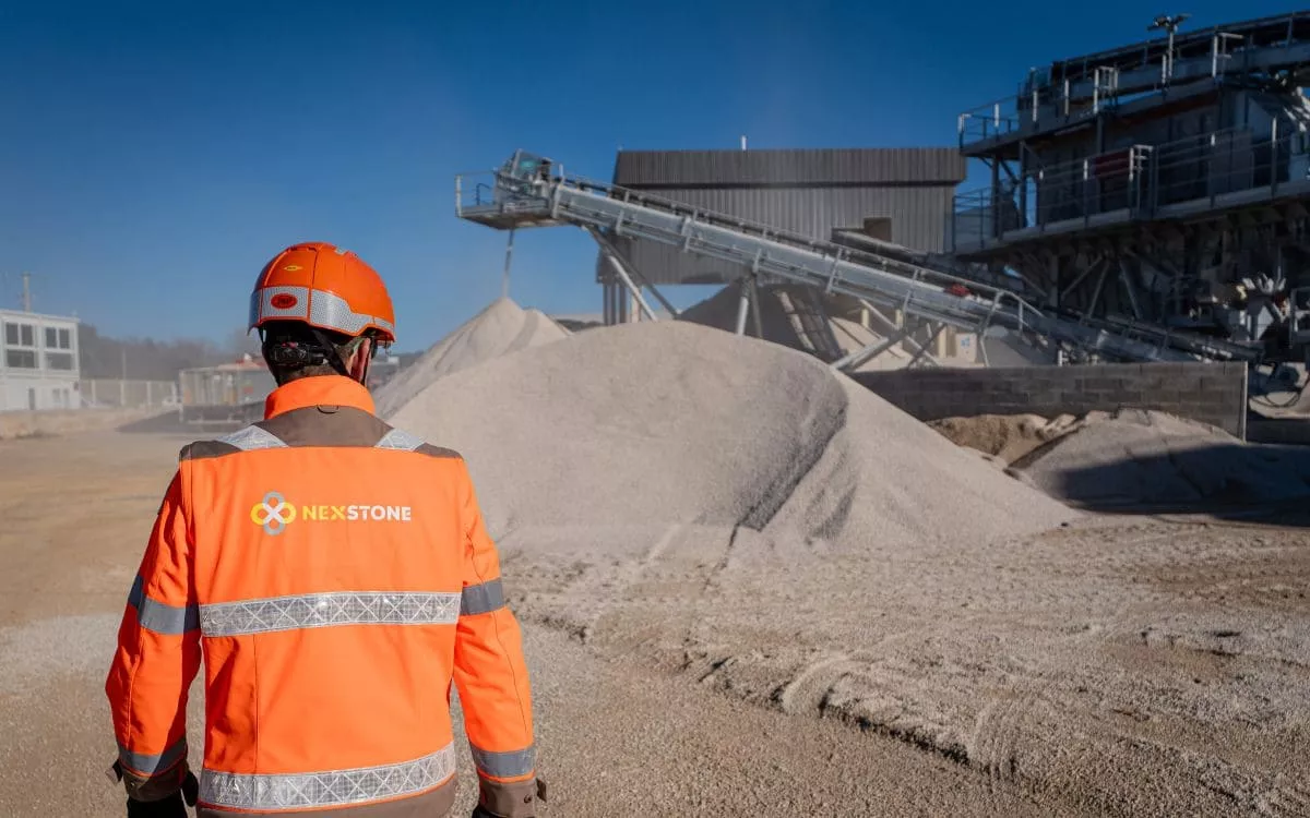 Collaborateur Nexstone en tenue de sécurité sur site de production de granulats, supervisant les matériaux destinés aux chantiers de construction