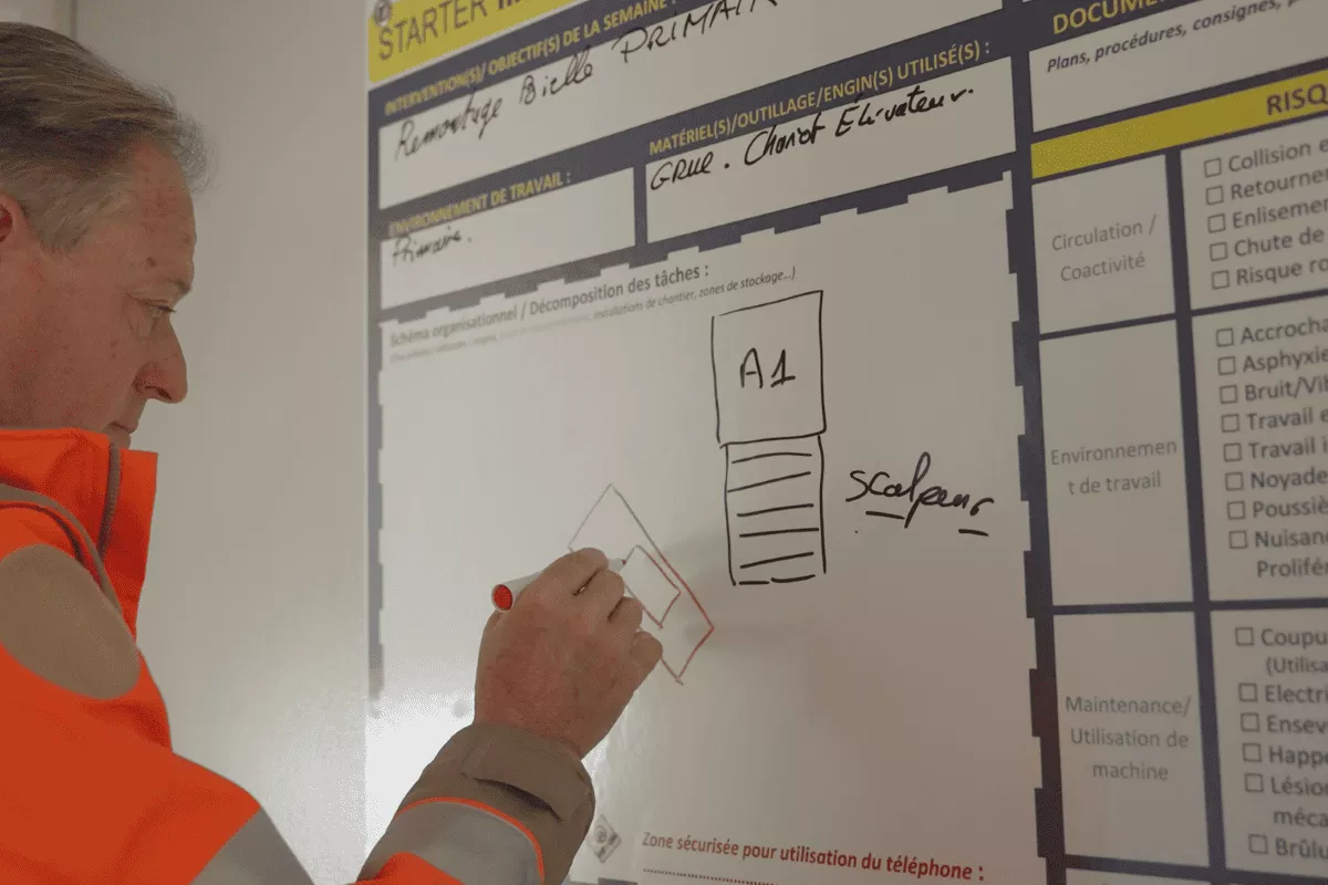 Chef de carrière Nexstone en tenue de sécurité complétant un tableau de préparation des travaux (planification, analyse des tâches et des risques), illustrant l’organisation et la prévention sur site.