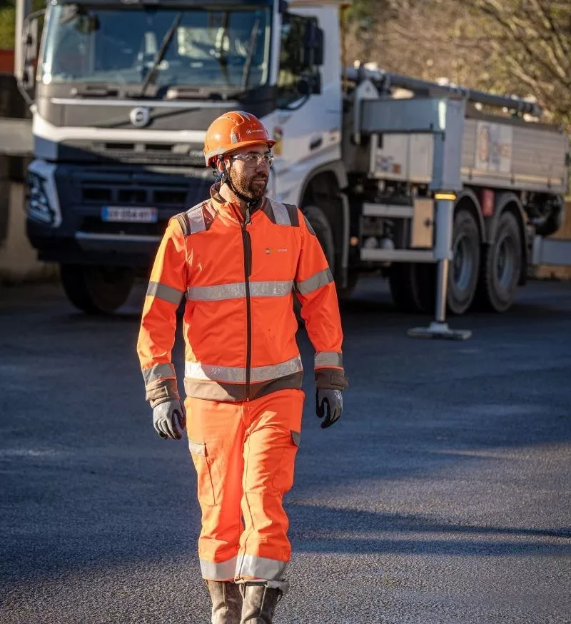 Collaborateur Nexstone en EPI sur site industriel avec camion pour logistique des matériaux.