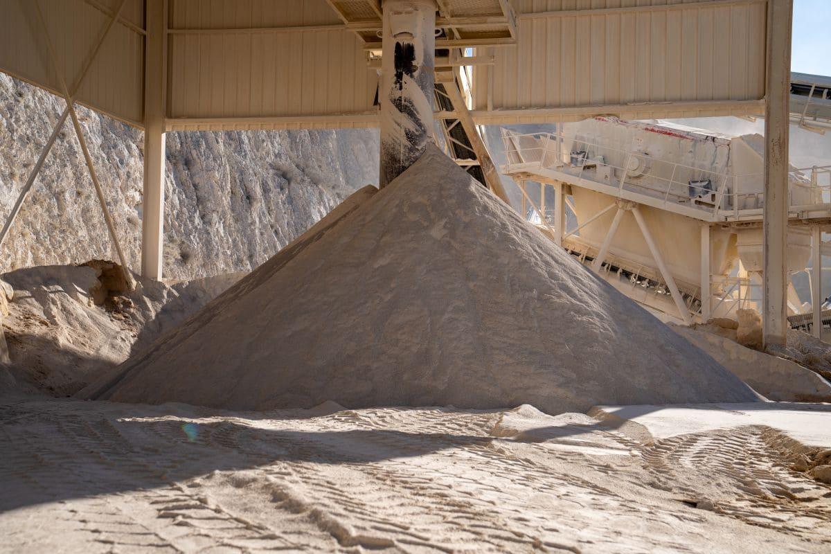 Stock de sable de carrière sous installation industrielle, granulat fin destiné aux travaux de construction et d’aménagement.