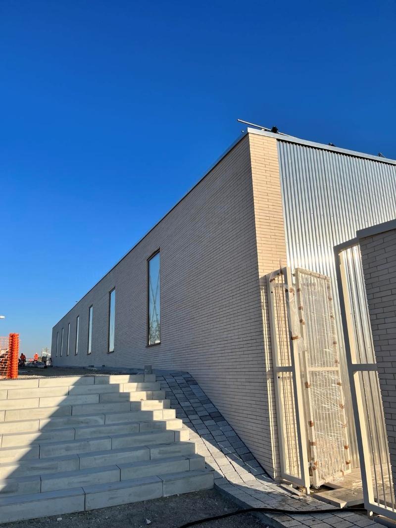 Bâtiment en briques avec façade moderne et aménagement extérieur en gradins et pavés.