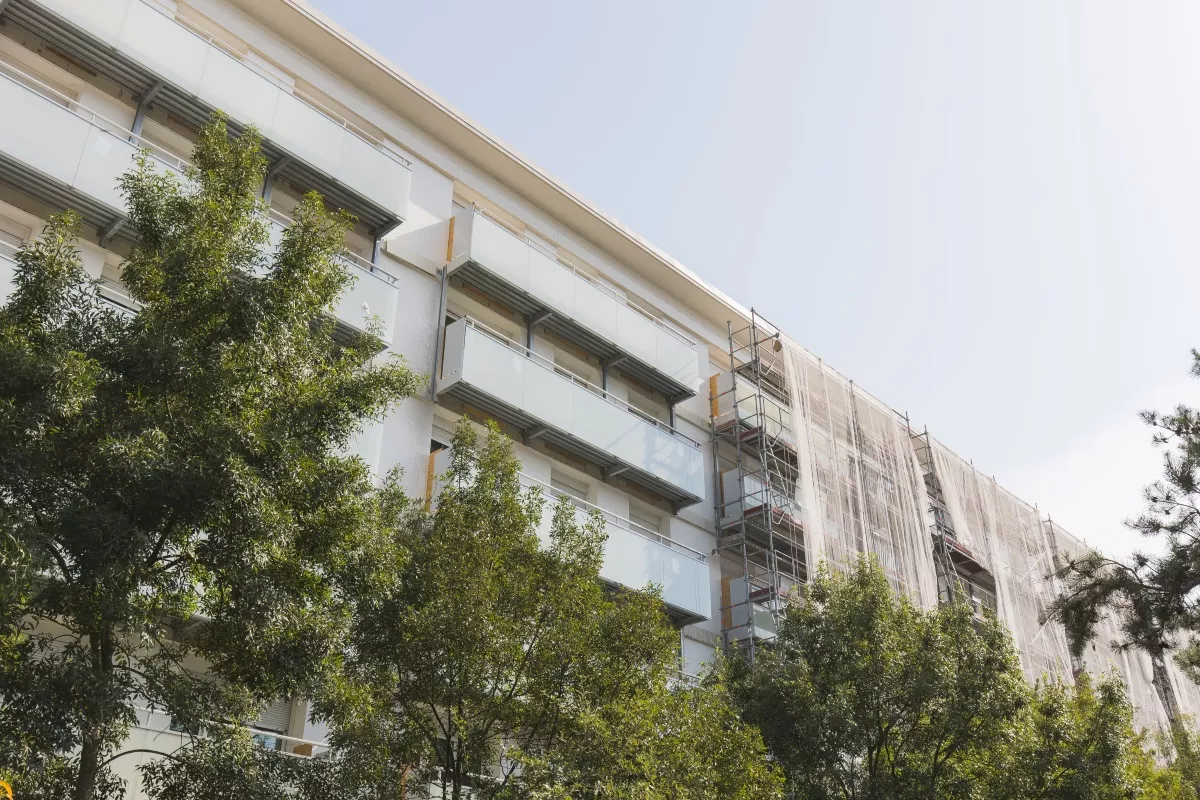 Immeuble résidentiel en cours de rénovation avec échafaudages et travaux de façade en milieu urbain.
