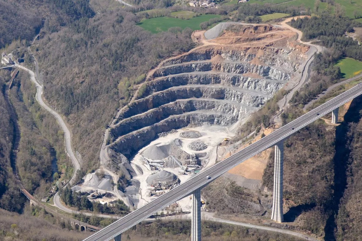 Carrière à ciel ouvert avec exploitation de granulats en terrasses, vue aérienne d’un site d’extraction de matériaux.