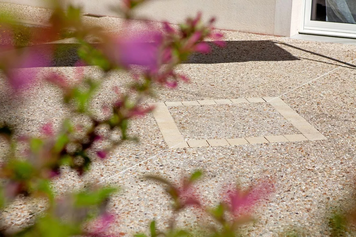 Terrasse en béton décoratif avec finition gravillonnée et motifs intégrés, aménagement extérieur esthétique.