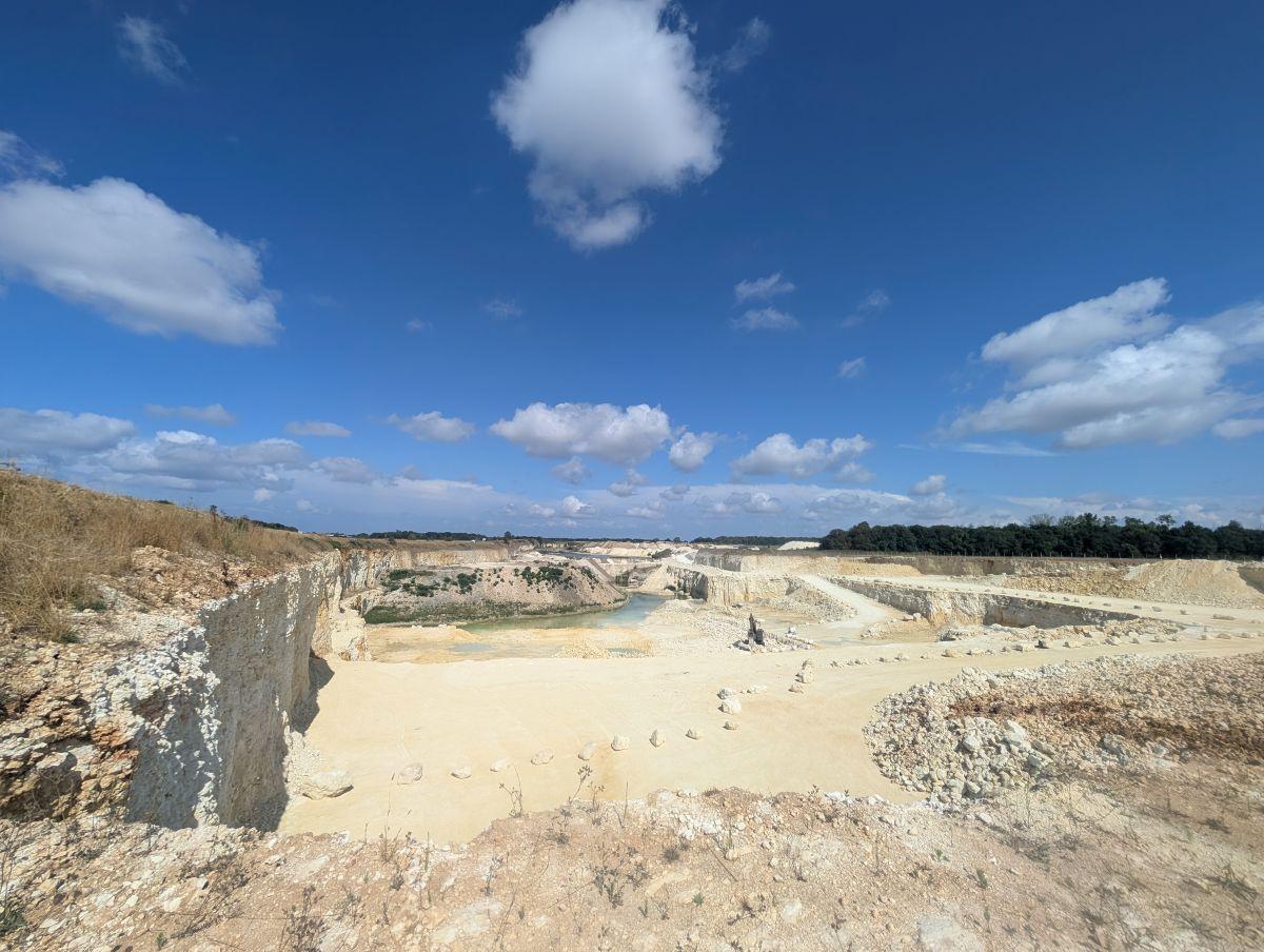 Vue d’ensemble d’une carrière de granulats en exploitation avec fronts de taille, pistes et zones d’extraction minérale