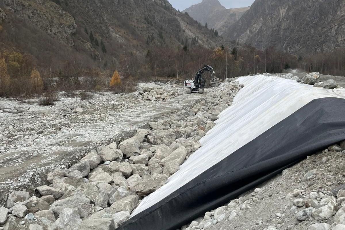 Enrochement en blocs de roche naturelle pour protection de berge et stabilisation de terrain en zone montagneuse, avec aménagement d’infrastructure hydraulique.