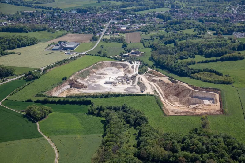 Vue aérienne de la carrière Nexstone de Scey-sur-Saône en Haute-Saône, entourée de prairies et de zones boisées.