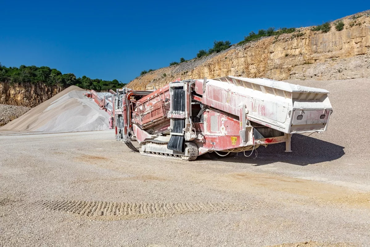 Installation mobile de traitement des granulats devant un front calcaire à la carrière Nexstone de Sombacour dans le Doubs.