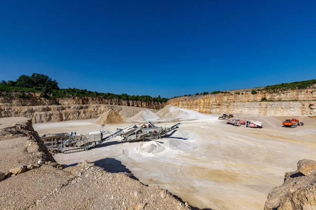 Installations de traitement et stocks de granulats au pied des fronts calcaires de la carrière Nexstone de Sombacour dans le Doubs.
