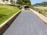 Terrain de pétanque en basalte avec revêtement minéral pour aménagement extérieur résidentiel.