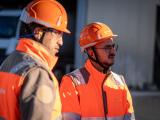 Collaborateurs Nexstone en tenue de sécurité (casques, vêtements haute visibilité) en échange sur site, illustrant le travail d’équipe et la coordination des opérations.