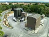 Centrale à béton de Cuxac-d’Aude vue aérienne, avec silos de stockage, zone de chargement des camions toupies et bâtiments techniques au cœur d’un site industriel entouré de végétation.
