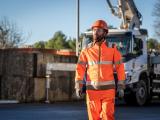 Chef de site Nexstone en tenue haute visibilité se déplaçant sur un site industriel, à proximité d’équipements et de zones de stockage de matériaux.