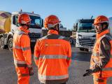 Équipe Nexstone en EPI coordonnant la logistique sur plateforme avec camions de transport de matériaux.