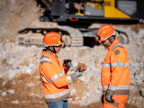 Collaborateurs Nexstone sur une carrière, en orange, des cailloux bruns et un engins