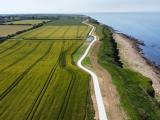 Chemin cyclable aménagé en sable 0/6 longeant le littoral, traversant des espaces agricoles et naturels avec vue sur la mer.