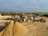 Vue de la carrière de Vauclerc avec son installation de concassage et de criblage, entourée de stocks de granulats destinés aux travaux de construction et d'aménagement.
